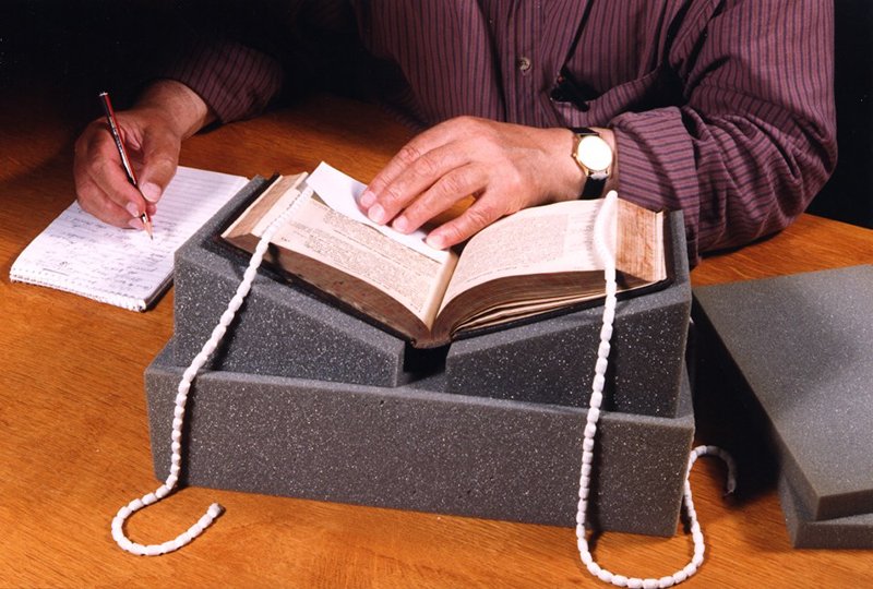 Two wedge-shaped supports being used, set apart to the width of the book’s spine.