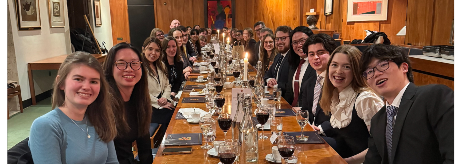 Society members wearing formal clothing seated at a long dining table for dinner
