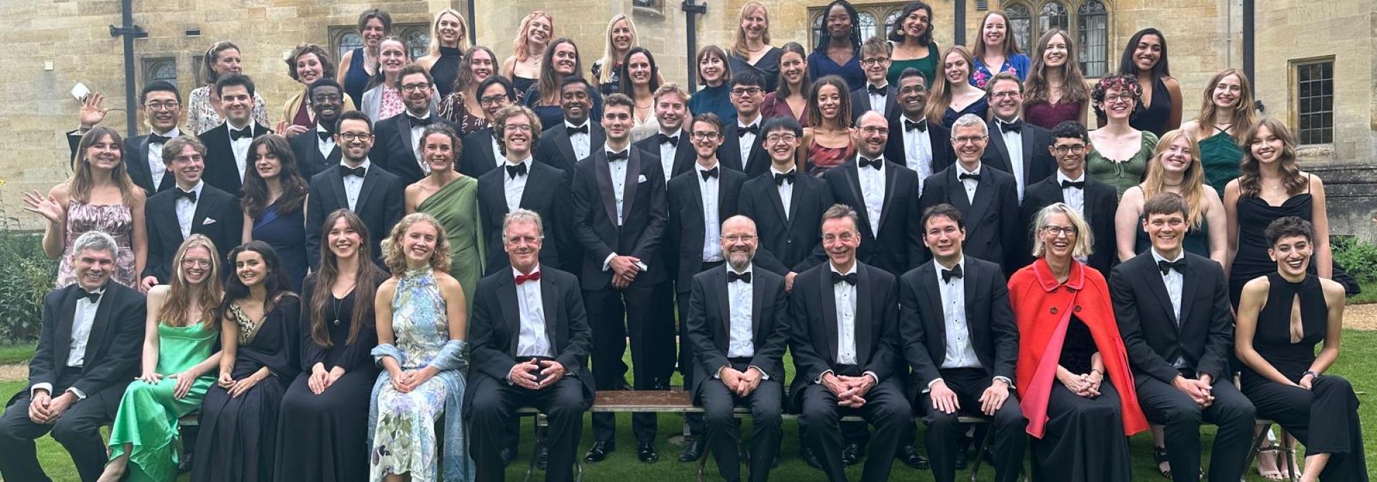 The Harvey Society Reunion in September 2024 Large group of students, alumni and fellows in formal dress posing in rows for the photo
