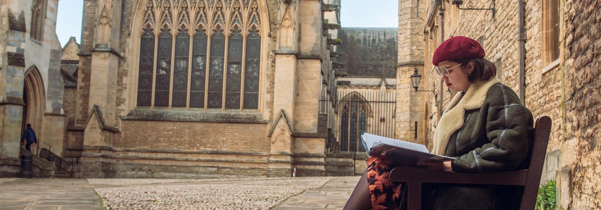 A student sitting on the bench in Front Quad.