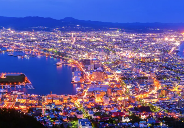 Overview of Hakodate at night, orange lights glow in a blue swathe of sea