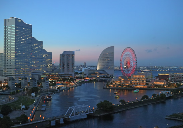 Yokohama at sunset, with skyscrapers and a large red ferris wheel against a pale blue sky