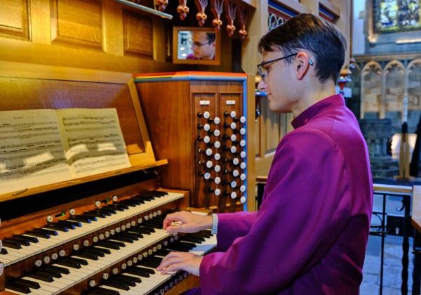 Francois Cloete wearing a maroon cassock at the Dobson Organ