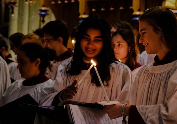 Choristers in front of the organ, lit by handheld candles