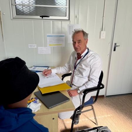 Professor Wilkinson OBE seeing a patient in the clinic in South Africa Professor Wilkinson OBE seated in the clinic with a patient seated with his back to the camera